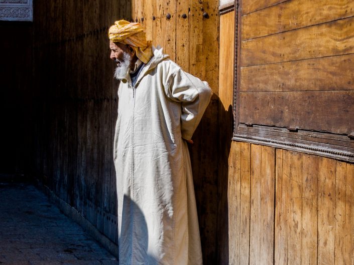 Morrocan elder wearing kaftan at his doorway, cat laying nearby