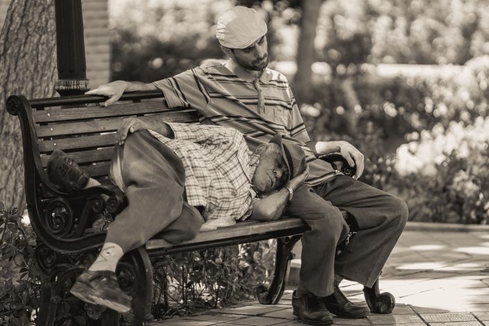 Father and son sleeping on a park bench