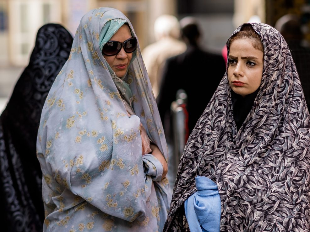 Mother and teenage daughter wearing chadors outside a mosque, Iran