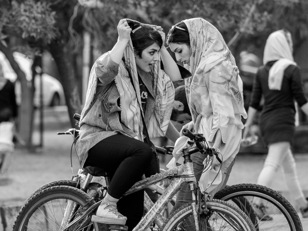Two young fashionable women riding bicycles, Iran