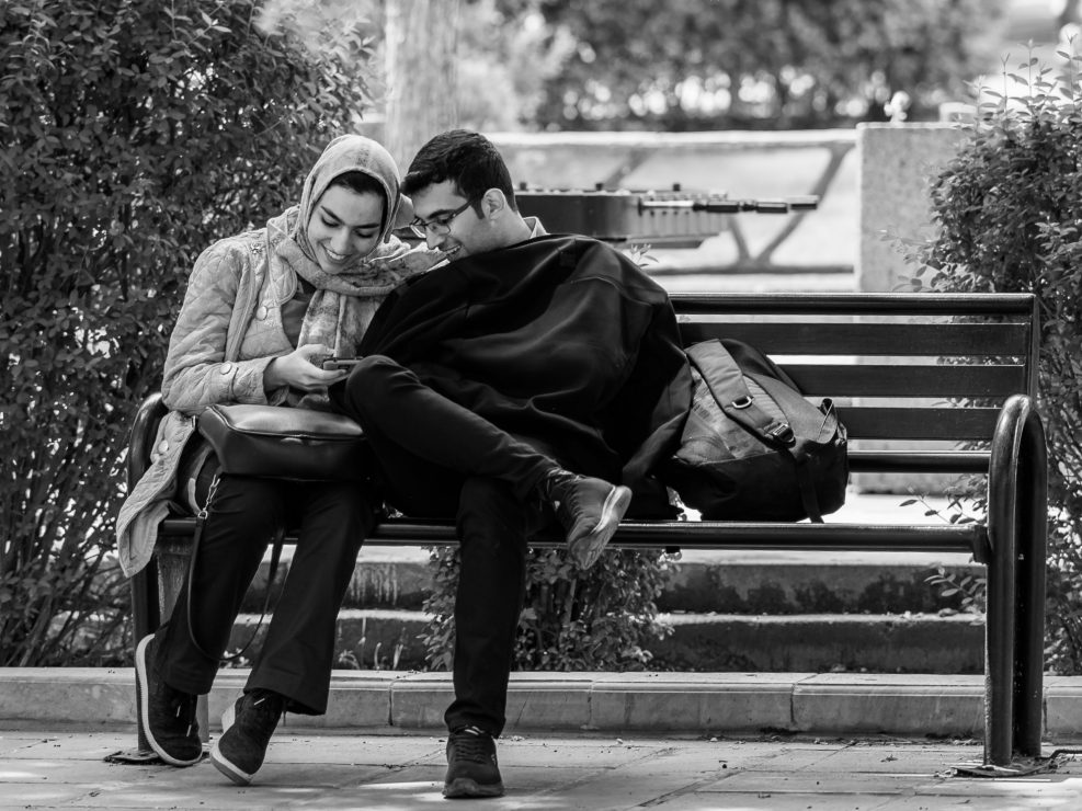 Couple sitting in a bench laughing, Iran