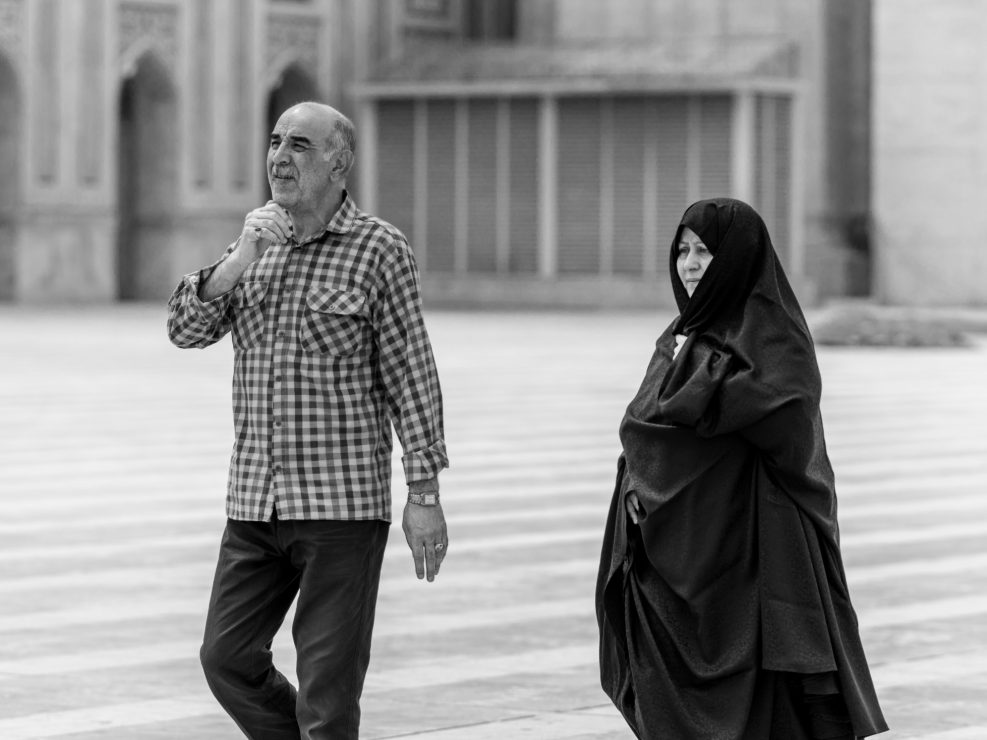 Couple, woman in long chador outside shrine, Iran