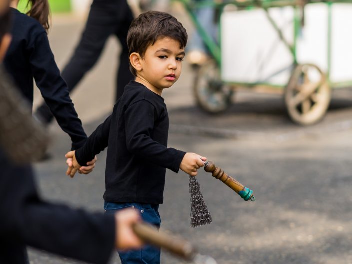 Little boy holding a Ashura chain upside down, Iran