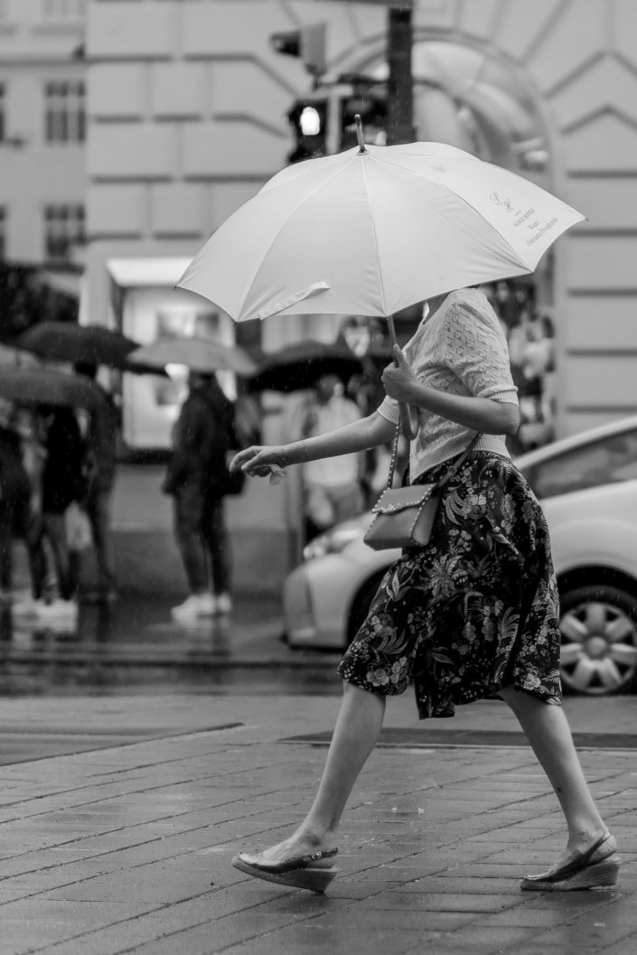 Woman with summer clothes hiding her face with an umbrella