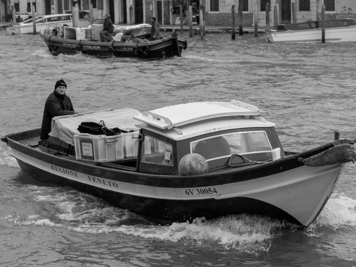 Venice Men driving boat transporting boxes for delivery